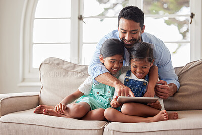 Buy stock photo Handsome single father spending quality time with his two daughters and using a digital tablet on the sofa at home