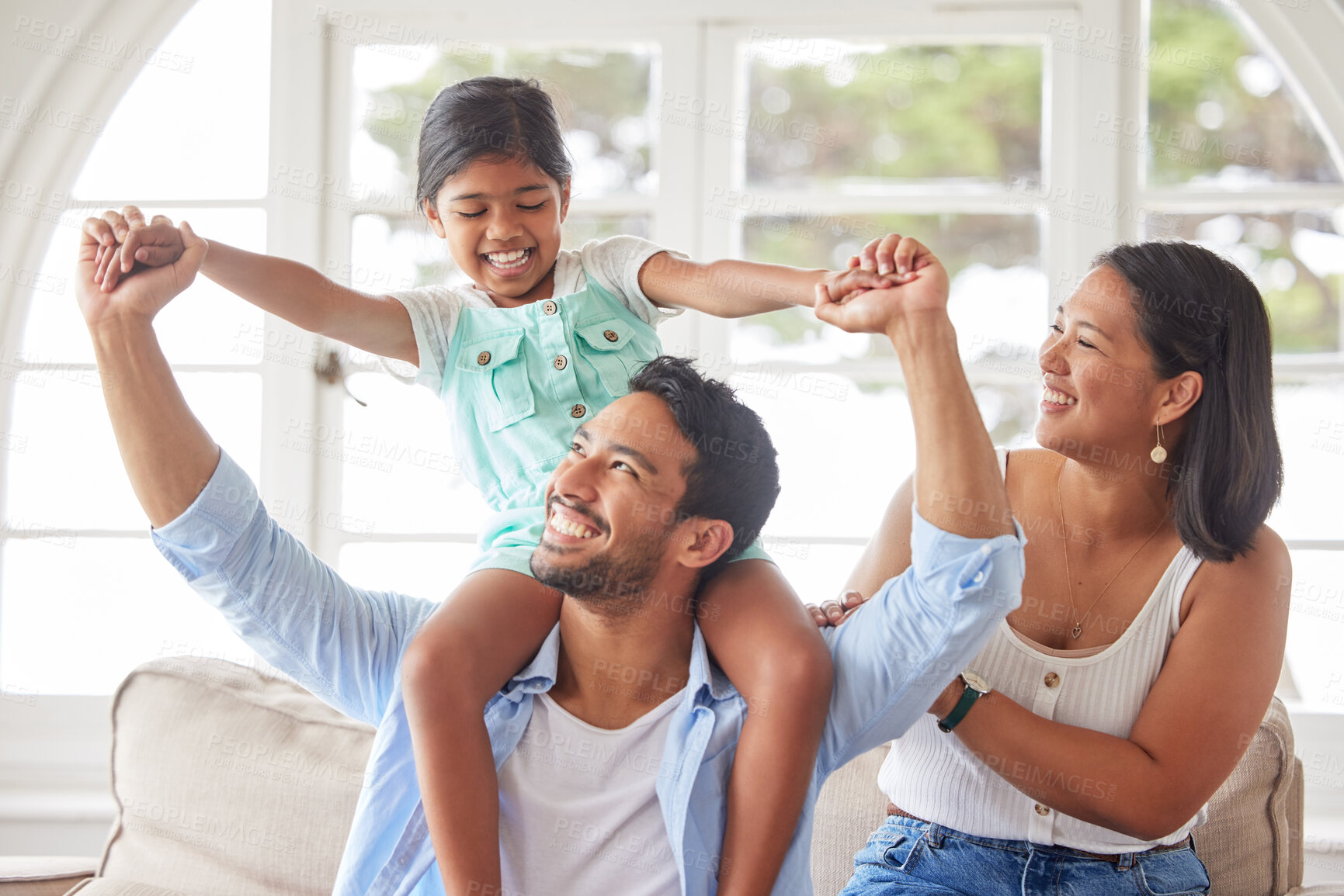 Buy stock photo Parents, girl child and piggyback in home with bonding, fun game and support with love, security and excited. Family, couple and playing with daughter on shoulders in living room for care or activity