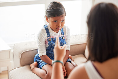 Buy stock photo Angry mother yelling at her naughty child about bad behaviour and pointing at a frowning, sad little girl at home