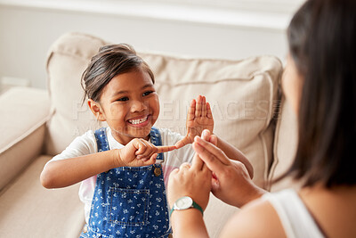 Buy stock photo Sign language, learning and girl kid with her mother in the living room of their family home. Happy, smile and child speaking with her hands to her deaf mom to communicate in their modern house.