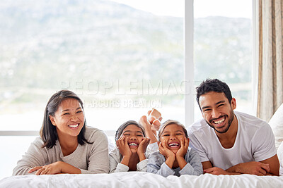 Buy stock photo Young couple looking happy and relaxed while sharing the bed with their daughters