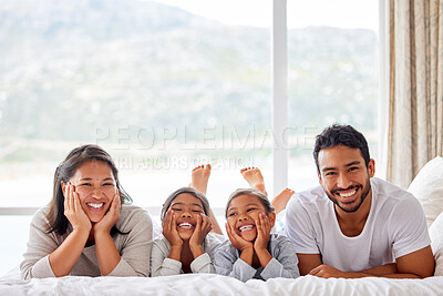 Happy family of four enjoying quality family time in bed at home
