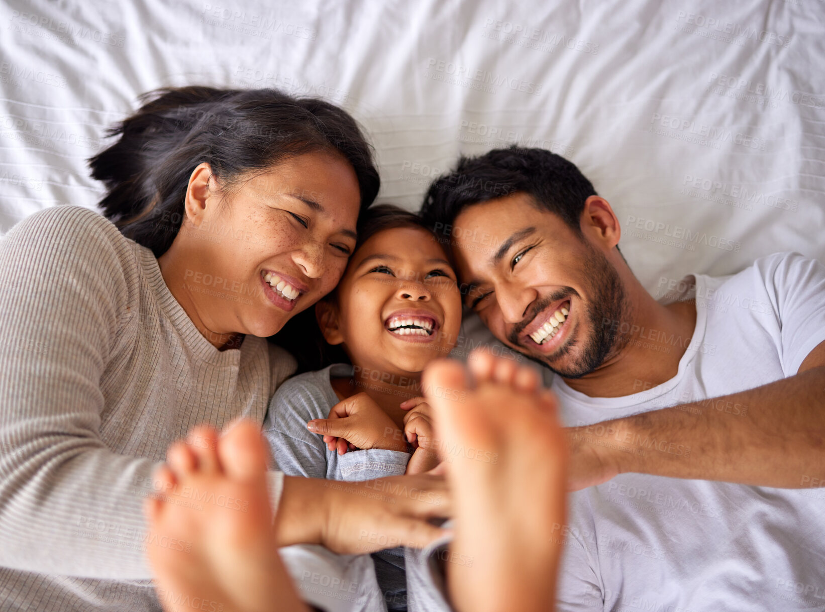 Buy stock photo Fun, bed and happy family playing, wake up and happy from above, tickle and laughing in their home. Bedroom, games and girl with parents, smile and laugh, relax and love in their house on the weekend