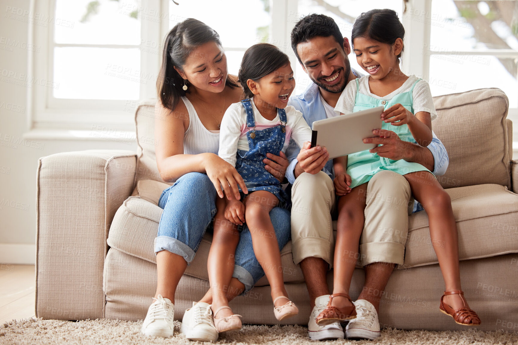 Buy stock photo Young happy family spending quality time together on a sofa and using a digital tablet to watch their favourite shows at home