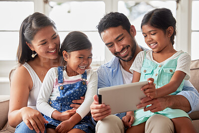 Content happy family smiling while using a digital tablet and choosing what to watch at home together on a sofa