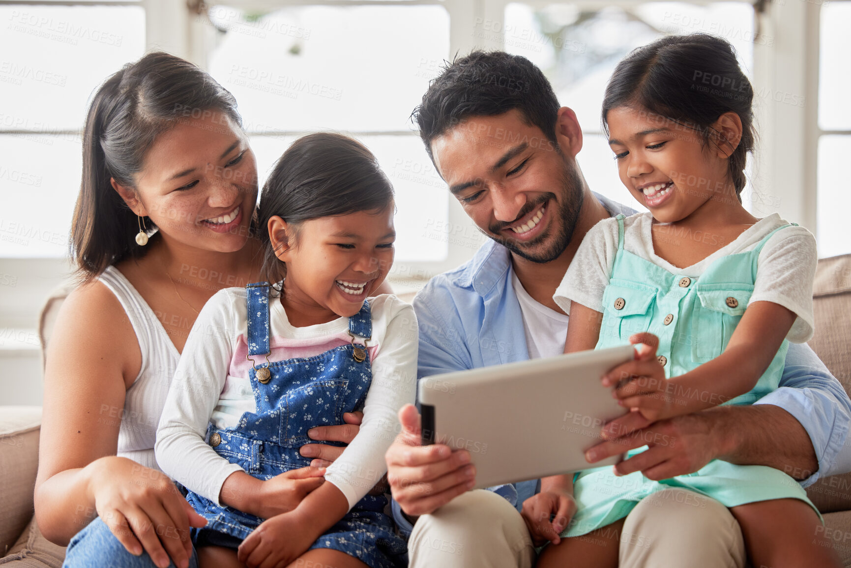 Buy stock photo Parents, girl and children with tablet on sofa with application, laugh or happy for show in family home. Father, mother and daughter kids with streaming, subscription or relax with movie in Indonesia