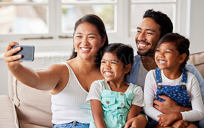 Buy stock photo Smiling family using a cellphone to take a selfie together while smiling and looking carefree on the sofa at home