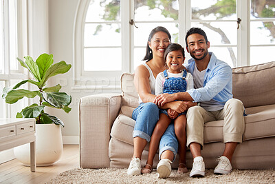 Buy stock photo Smiling happy young ethnic family being affectionate and enjoying the weekend with their child while relaxing on a sofa at home