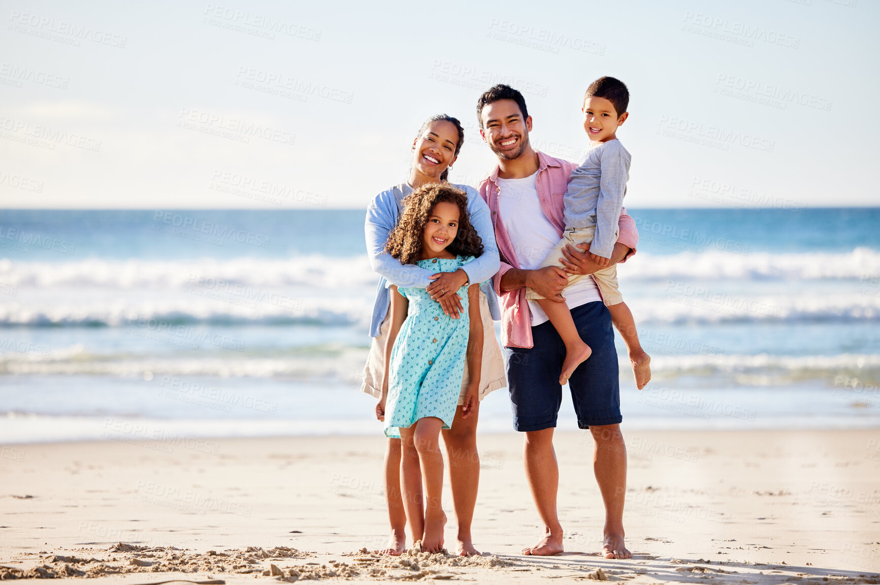 Buy stock photo Shot of a young couple and their two children spending the day together at the beach