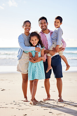 Buy stock photo Shot of a young couple and their two children spending the day together at the beach