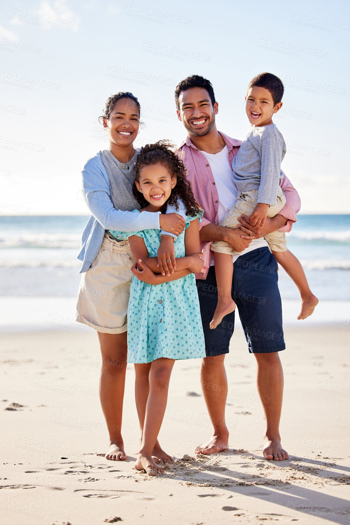 Buy stock photo Shot of a young couple and their two children spending the day together at the beach