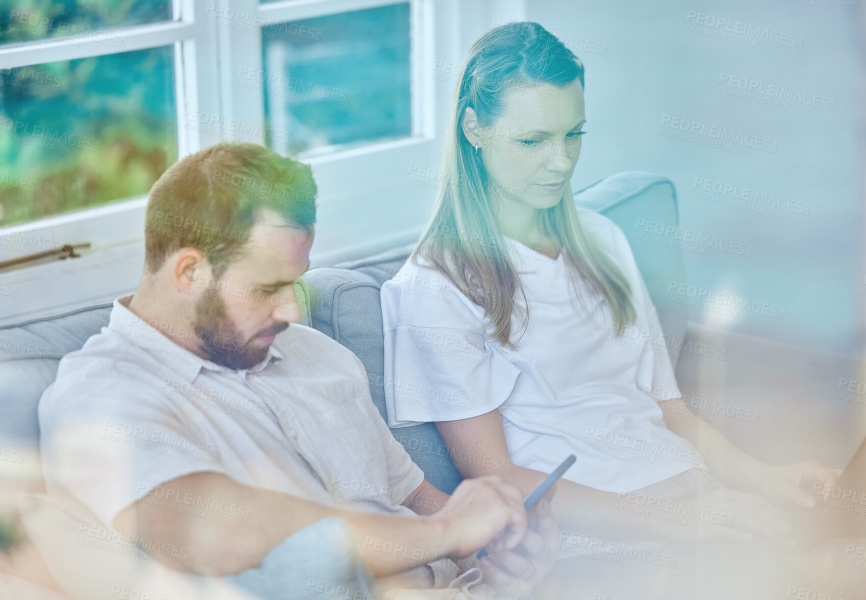 Buy stock photo Shot of a young couple sitting on the couch at home