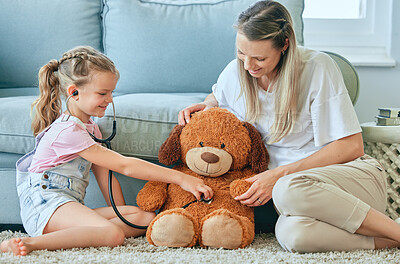 Buy stock photo Shot of a little girl and her mother playing doctor with a teddybear at home