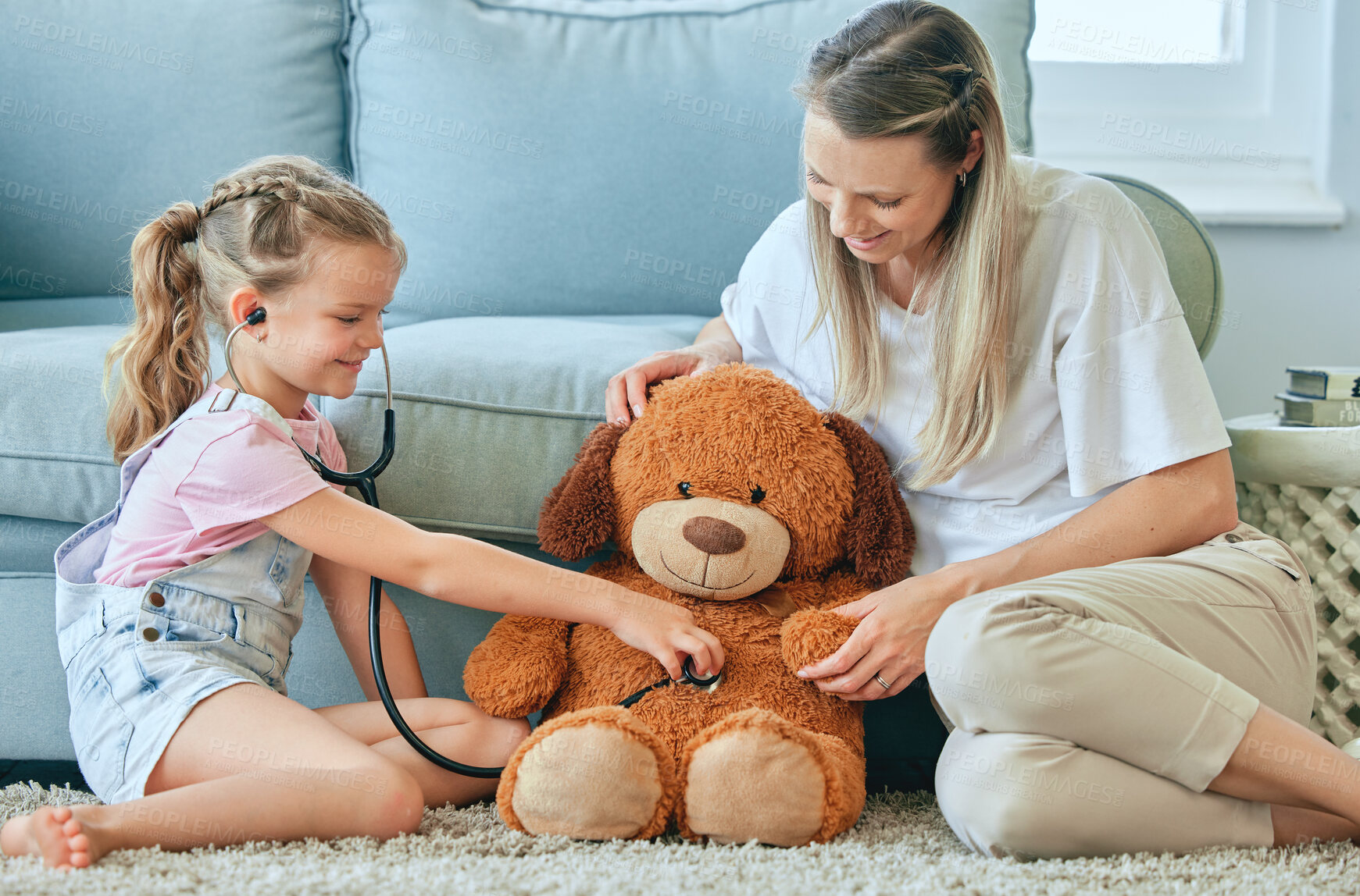 Buy stock photo Shot of a little girl and her mother playing doctor with a teddybear at home