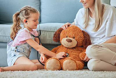 Buy stock photo Shot of a little girl and her mother playing doctor with a teddybear at home