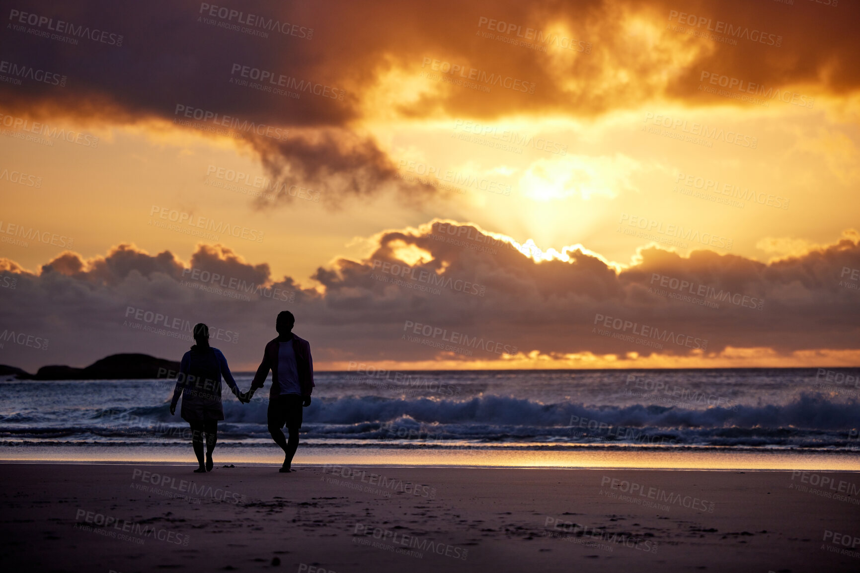 Buy stock photo Sunset, seaside and couple with love, holding hands and romance with tropical island, travel and honeymoon. Beach, golden hour and man with woman, relationship and holiday for anniversary or vacation