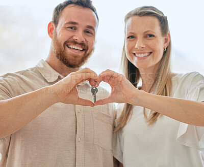 Buy stock photo Shot of a young couple making a heart gesture with their hands while holding the keys to their new house