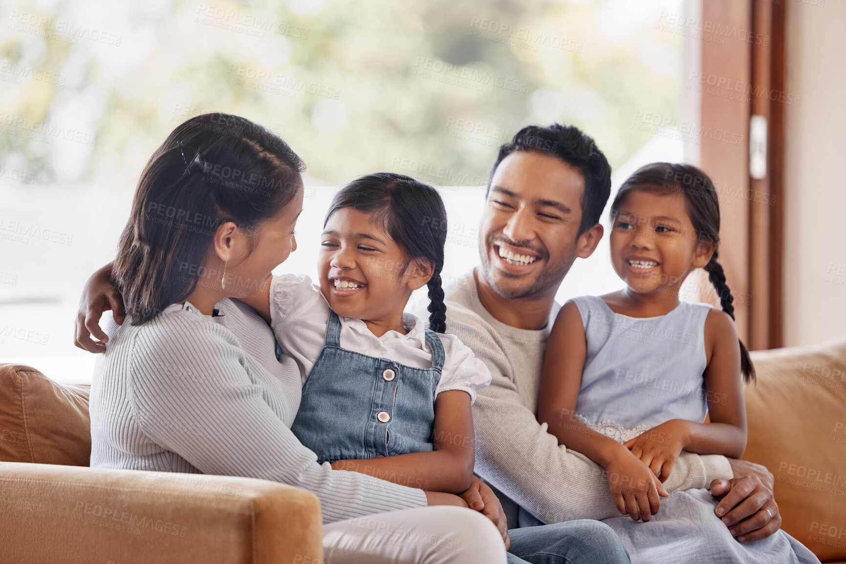 Buy stock photo Cropped shot of an affectionate young family of four sitting on the sofa at home