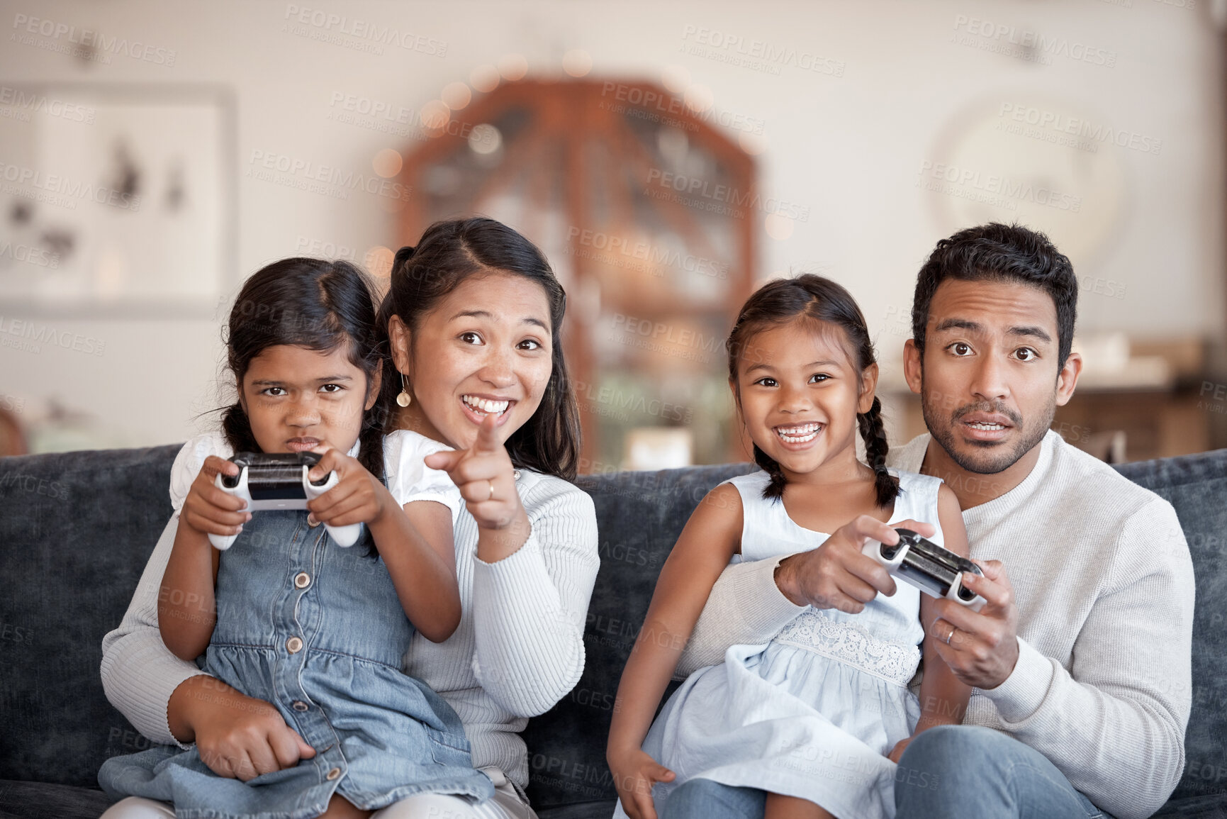 Buy stock photo Cropped portrait of an affectionate young family of four playing video games in the living room at home
