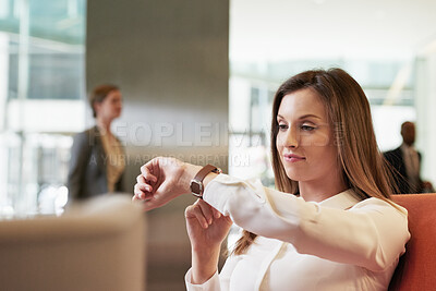 Business woman checking her watch while sitting in airport waiting lounge for business travel