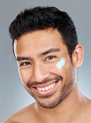 Buy stock photo Man, studio and facial portrait with moisturizer for skincare or wellness, beauty or lotion cosmetic for aesthetics. Male person, cream and face with happiness on gray background, glow or smile