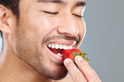 Buy stock photo Man, fruit and beauty studio for wellness, eating strawberry and natural teeth whitening on background. Asian, male model and eyes closed or happy, organic and brightening antioxidants for oral care