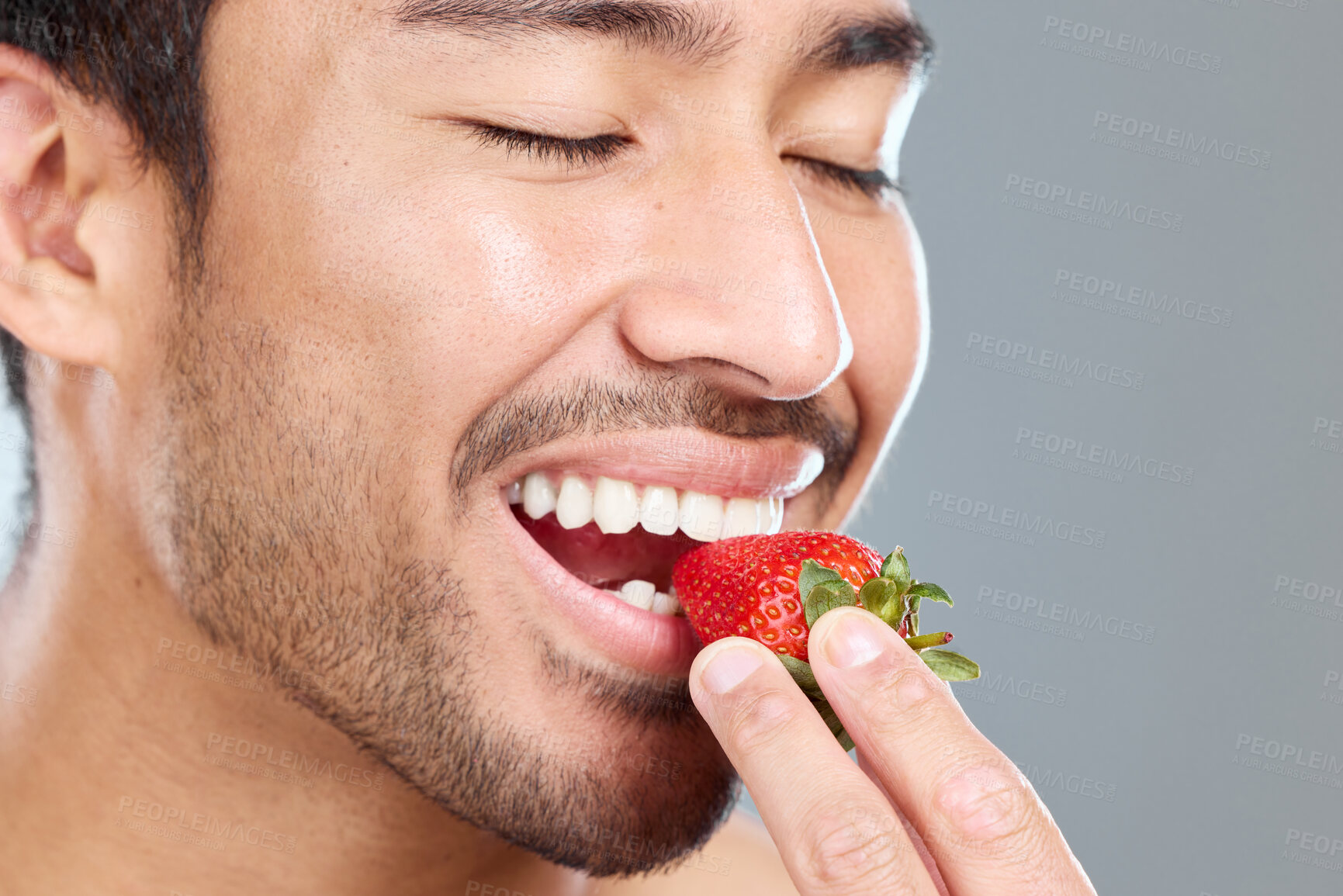 Buy stock photo Man, fruit and beauty studio for wellness, eating strawberry and natural teeth whitening on background. Asian, male model and eyes closed or happy, organic and brightening antioxidants for oral care