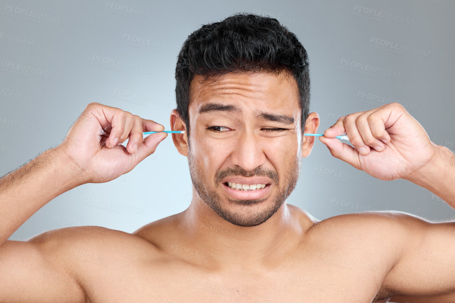 Buy stock photo Man, cotton bud and ears in studio for cleaning, hygiene and morning routine. Male person, earbuds and wax removal on gray background for grooming, regret and unpleasant feeling for body care