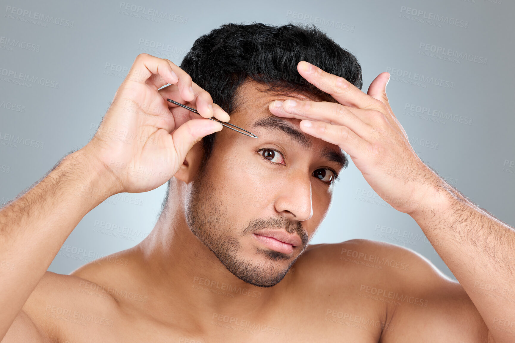 Buy stock photo Man, portrait and tweezers by eyebrow in studio for grooming, facial epilation and wellness or skincare. Male person, cosmetic tool and product for hair removal, gray background and hygiene routine.
