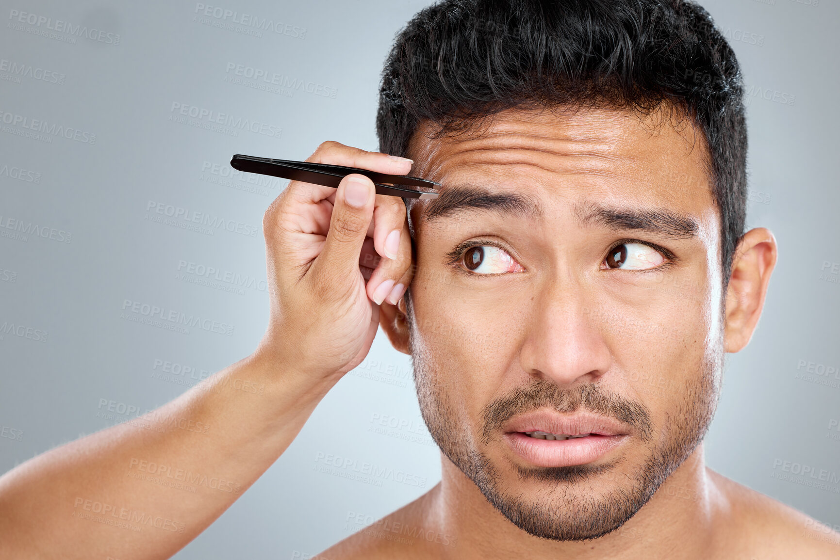Buy stock photo Man, hand and tweezers by eyebrow in studio for grooming, facial epilation and maintenance or skincare. Male person, cosmetic tool and product for hair removal, gray background and hygiene routine.
