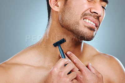 Buy stock photo Frustrated man, hands and shaving neck with razor blade for grooming, skincare or irritation on a blue studio background. Closeup, male person or young model with tool for hair removal in discomfort