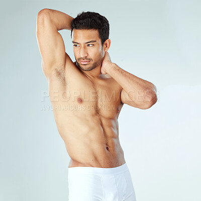 Buy stock photo Shot of a handsome muscular man posing against a studio background