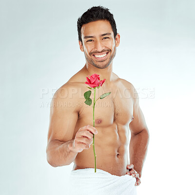 Buy stock photo Shot of an attractive young man holding a rose against a studio background