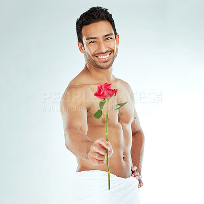 Buy stock photo Shot of an attractive young man holding a rose against a studio background