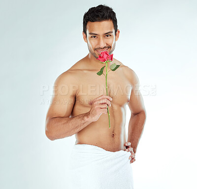 Buy stock photo Shot of an attractive young man holding a rose against a studio background