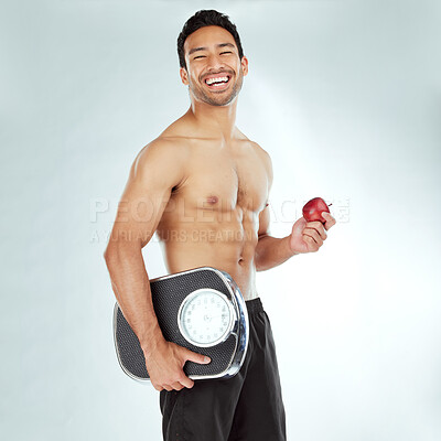 Buy stock photo Health, scale and portrait of fitness man with apple in studio for weight loss, diet or detox on white background. Nutrition, balance or face of wellness model smile for superfoods, fruit or progress