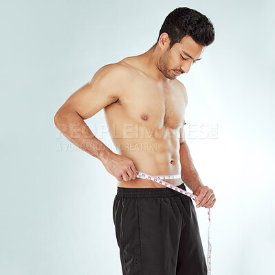 Buy stock photo Stomach, measuring tape and fitness man in studio with Weight loss, progress or bmi control on white background. Body, wellness and male model with waist measurement for diet, health or sixpack check