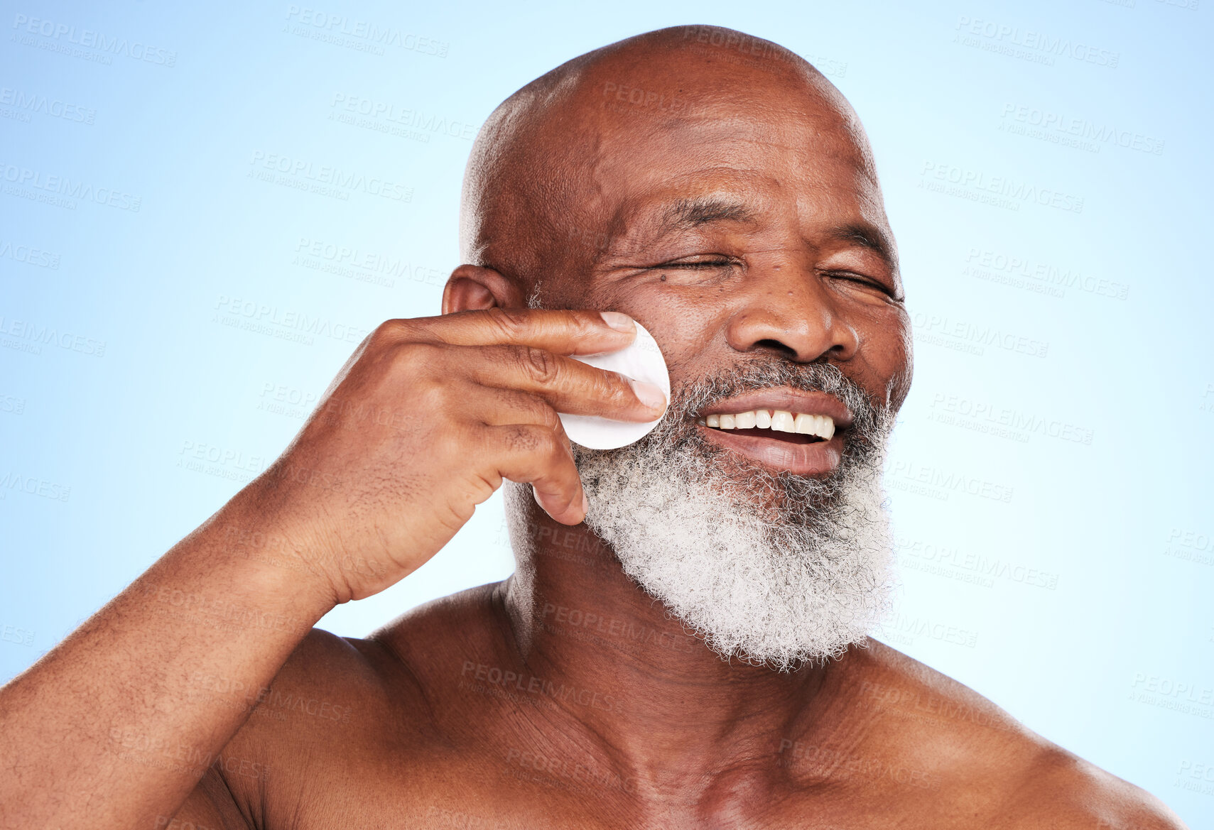 Buy stock photo Black man, smile and skincare in studio with cotton pad for cleaning, toner and skin moisturizer. Mature person, happy and dermatology on blue background with beauty swab for wellness or treatment