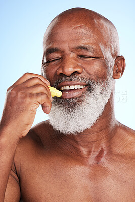 Buy stock photo Lip balm, skincare and mature black man in studio with health, natural and facial routine. Smile, beauty and African male person with chapstick for mouth hydration with grooming by blue background.