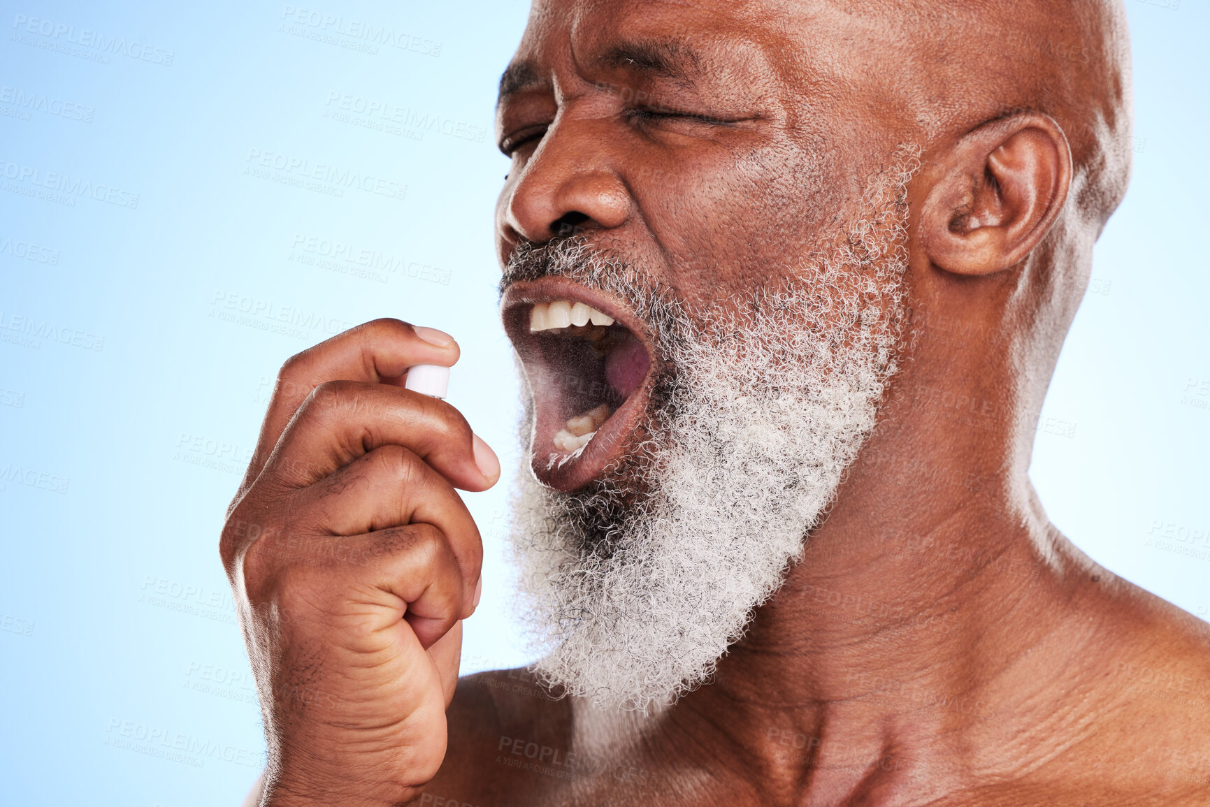 Buy stock photo Mouth, bottle and black man with spray in studio for oral hygiene, cleaning and fresh breath. Dental, mist and senior person with product on blue background for halitosis, grooming and odor removal