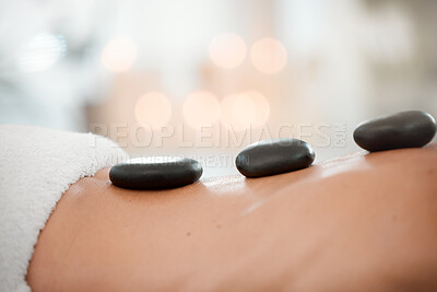 Buy stock photo Shot of a woman resting with hot stones on her back during a trip to the spa