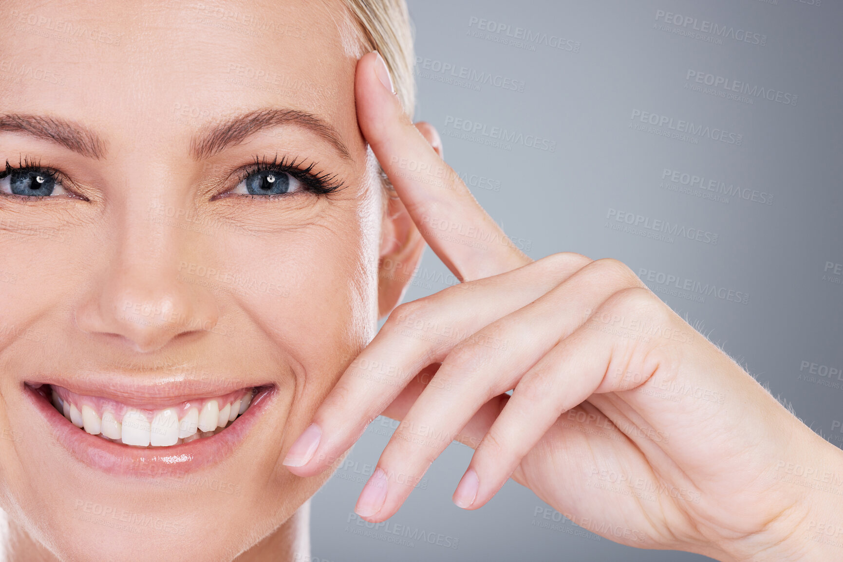 Buy stock photo Studio portrait of an attractive mature woman touching her face against a grey background