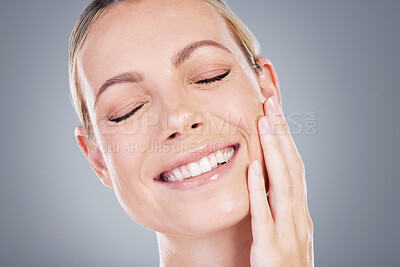 Buy stock photo Studio shot of an attractive mature woman touching her face against a grey background