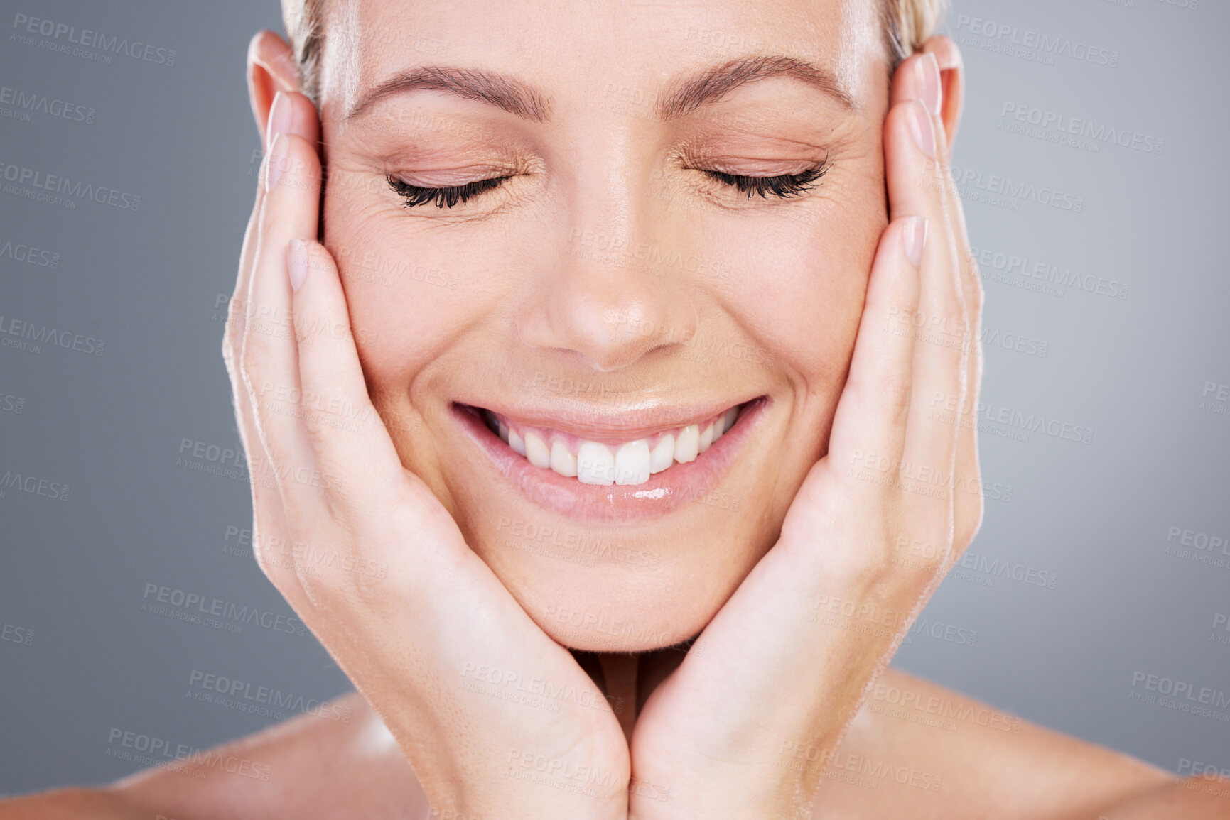 Buy stock photo Eyes closed, happy and woman in studio for skincare, wellness and facial treatment. Dermatology, salon and person with hands on face for health, cosmetics and natural beauty on gray background