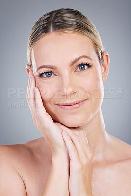 Buy stock photo Studio portrait of an attractive mature woman touching her face against a grey background