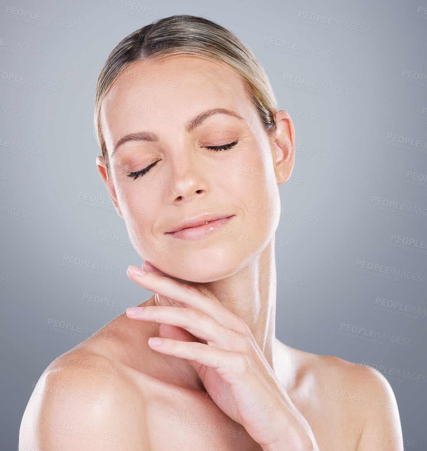 Buy stock photo Studio shot of an attractive mature woman touching her face against a grey background