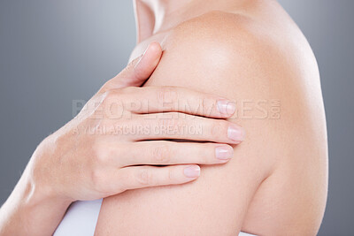 Buy stock photo Studio shot of an unrecognisable woman touching her arm against a grey background