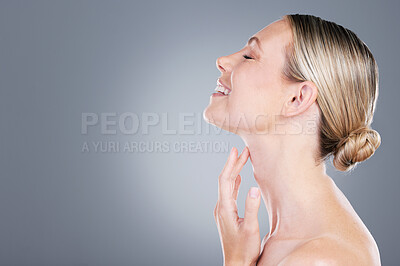Buy stock photo Studio shot of an attractive mature woman touching her neck against a grey background