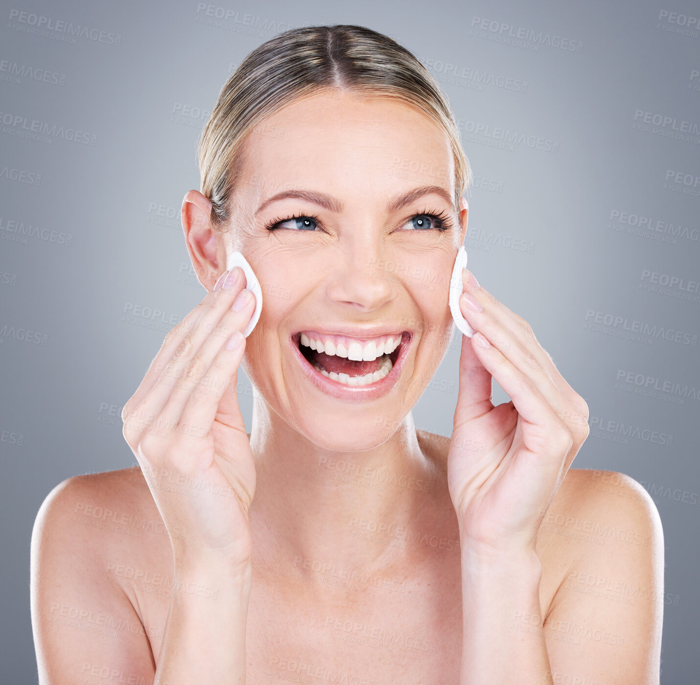 Buy stock photo Happy woman, cotton pad and cosmetics with beauty for skincare, foundation or makeup removal on a gray studio background. Young female person or model with smile or patch on cheek in facial treatment