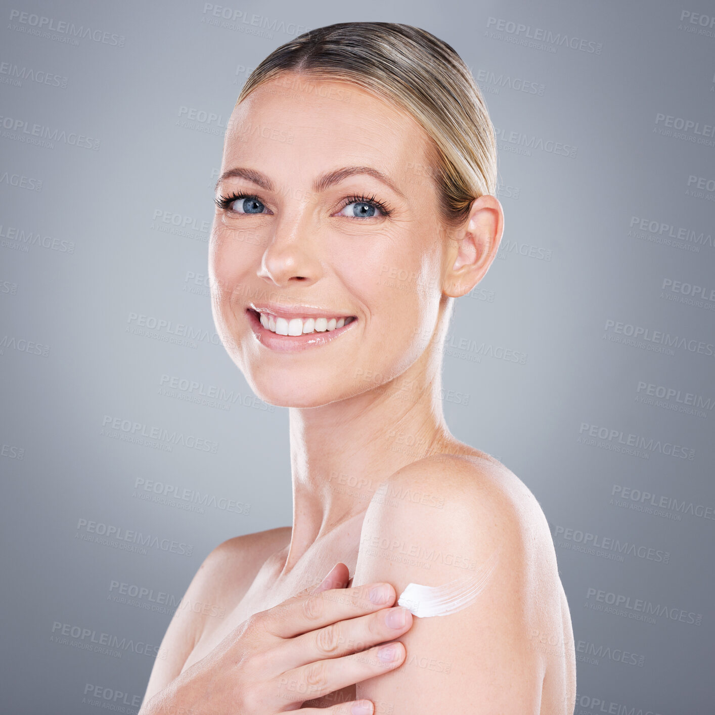 Buy stock photo Happy woman, portrait and cream with shoulder for skincare or moisturizer on a gray studio background. Young female person or model with smile for anti aging treatment, lotion or cosmetic ointment